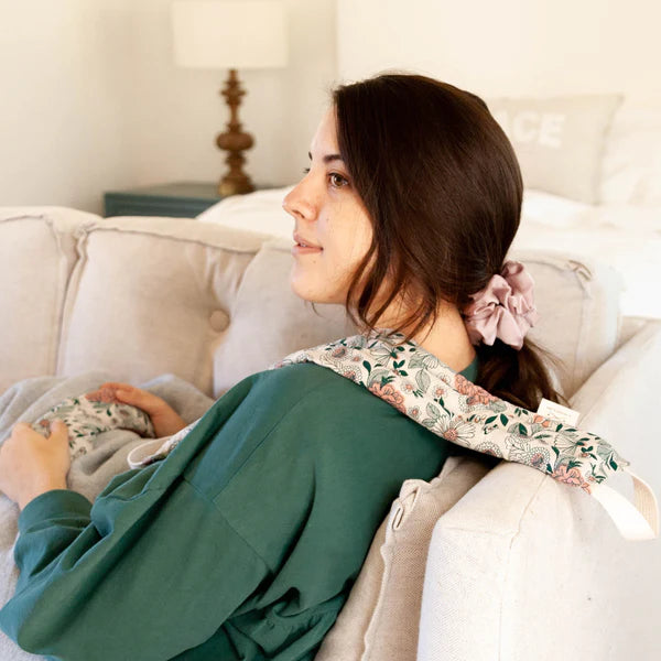 Woman on a couch wearing the Slow North Hot + Cold Neck Wrap in Hidden Falls over her shoulders