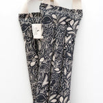 Slow North Hot + Cold Neck Wrap in Mystical Mushroom, a black wrap with cream mushroom line art, laid flat