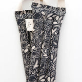 Slow North Hot + Cold Neck Wrap in Mystical Mushroom, a black wrap with cream mushroom line art, laid flat
