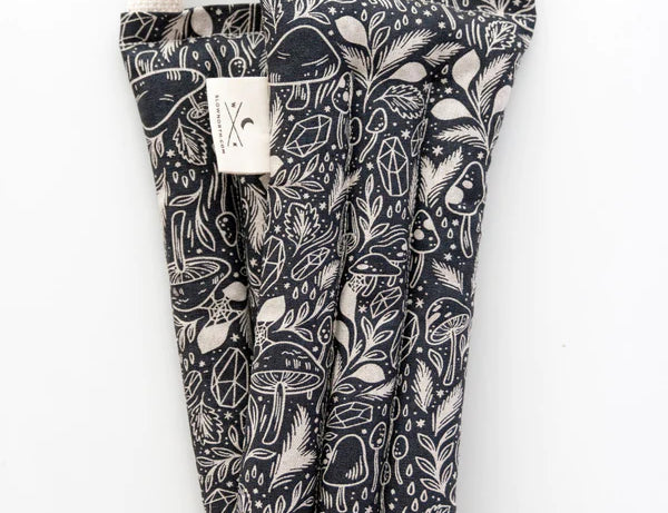 Slow North Hot + Cold Neck Wrap in Mystical Mushroom, a black wrap with cream mushroom line art, laid flat