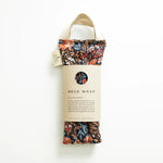 Slow North Hot + Cold Neck Wrap in Pom Blossom, a navy floral wrap with a kraft Neck Wrap sleeve