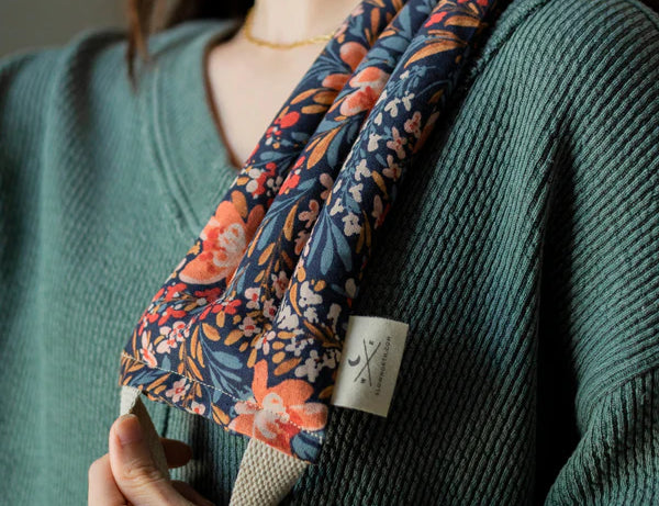 Woman in a green sweater wearing the Slow North Hot + Cold Neck Wrap in Pom Blossom over her shoulder