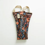 Slow North Hot + Cold Neck Wrap in Pom Blossom, a navy wrap with orange and blue florals, laid flat
