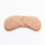 Slow North Migraine Mask in Copper Fields, a terracotta crosshatch print eye mask, laid flat