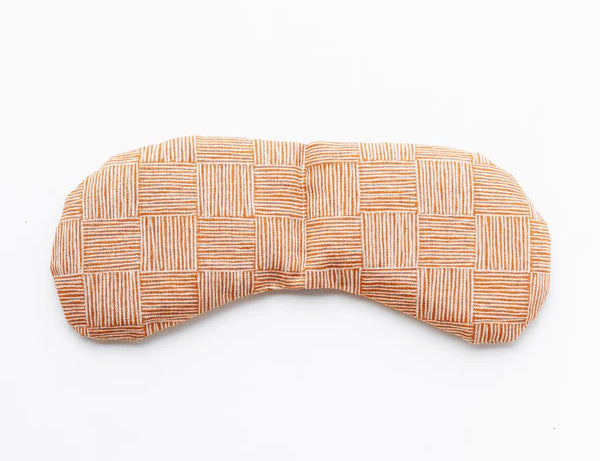 Slow North Migraine Mask in Copper Fields, a terracotta crosshatch print eye mask, laid flat