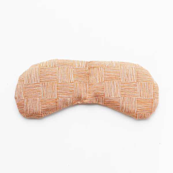 Slow North Migraine Mask in Copper Fields, a terracotta crosshatch print eye mask, laid flat