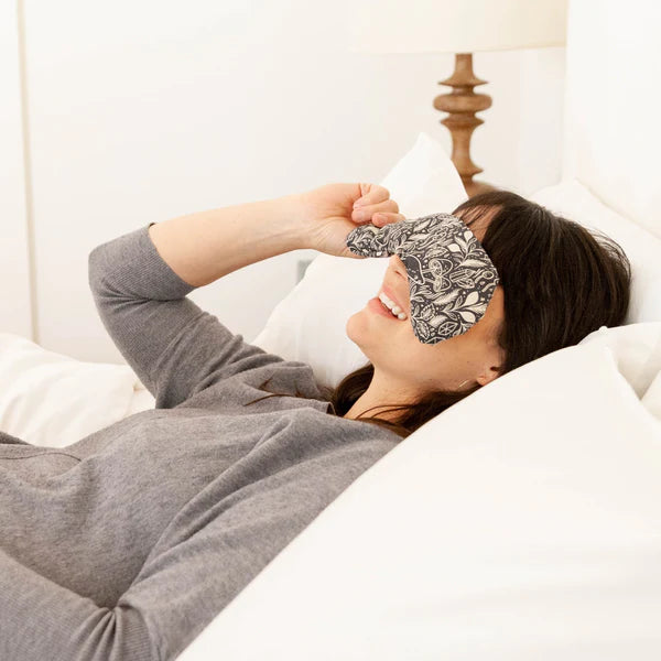 Woman lying in bed wearing the Slow North Migraine Mask in Mystical Mushroom