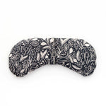 Slow North Migraine Mask in Mystical Mushroom, a black eye mask with cream mushroom line art, laid flat