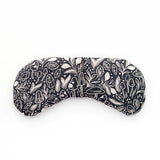Slow North Migraine Mask in Mystical Mushroom, a black eye mask with cream mushroom line art, laid flat