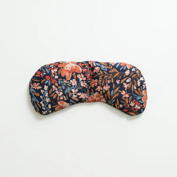 Slow North Migraine Mask in Pom Blossom, a navy eye mask with orange and blue florals, laid flat