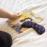 Slow North Migraine Mask in Solstice resting on a magazine on a bed