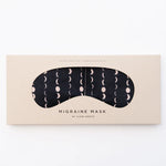 Slow North Migraine Mask in Solstice, a black eye mask with cream moon phases, on its kraft packaging card