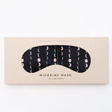 Slow North Migraine Mask in Solstice, a black eye mask with cream moon phases, on its kraft packaging card