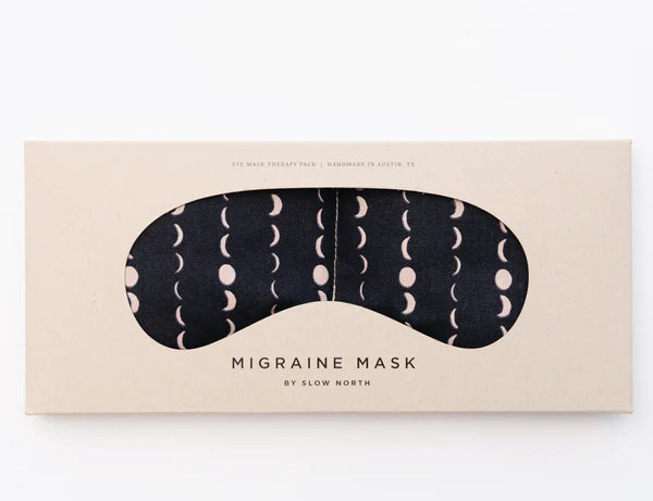 Slow North Migraine Mask in Solstice, a black eye mask with cream moon phases, on its kraft packaging card