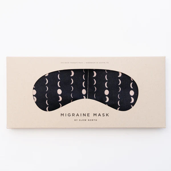 Slow North Migraine Mask in Solstice, a black eye mask with cream moon phases, on its kraft packaging card