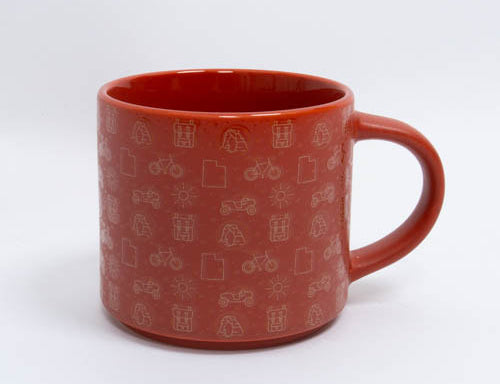 Red clay toned ceramic Moab mug patterned with arches, bikes and desert icons