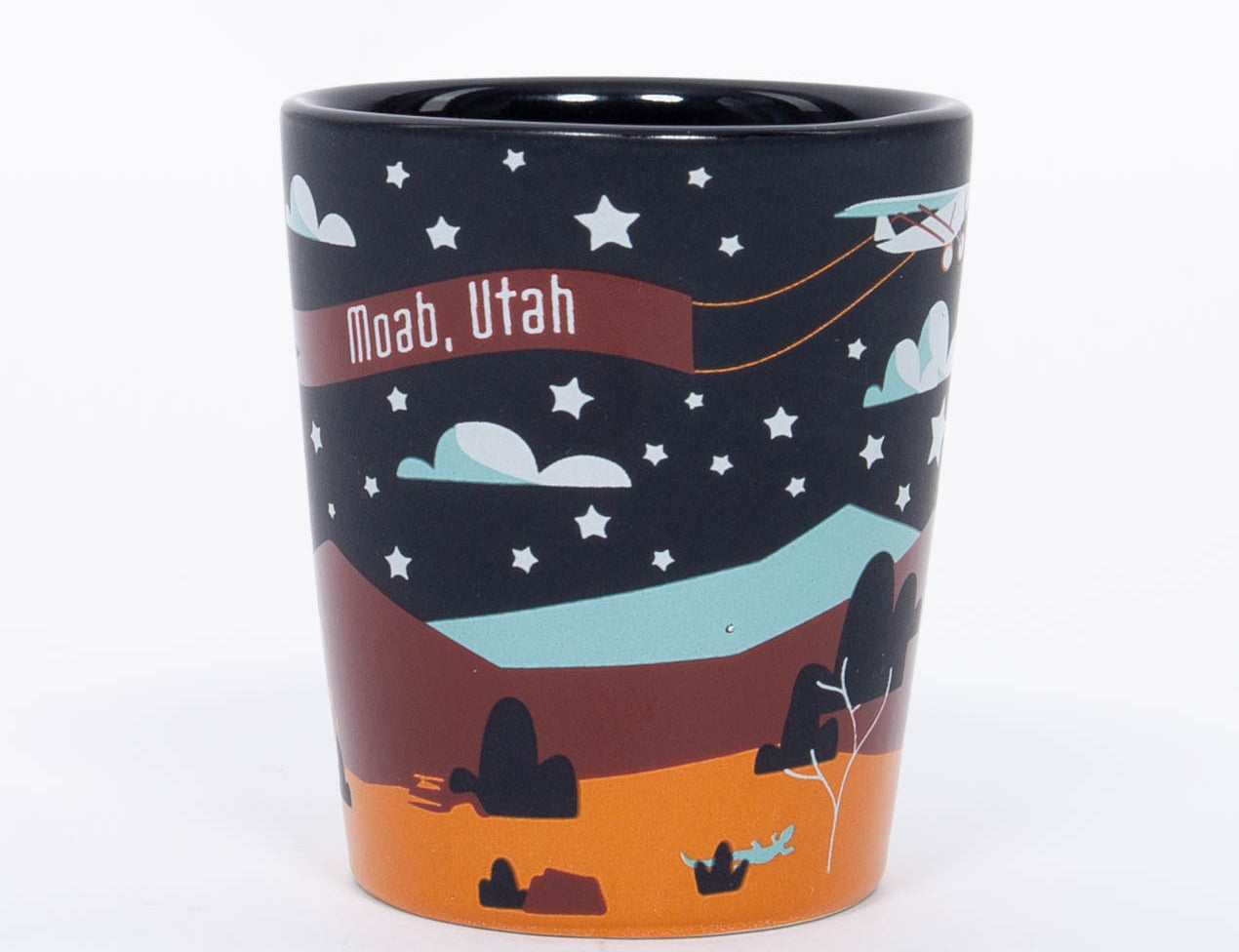 Navy ceramic Moab shot glass with a moon, stars and layered orange red rock, second view