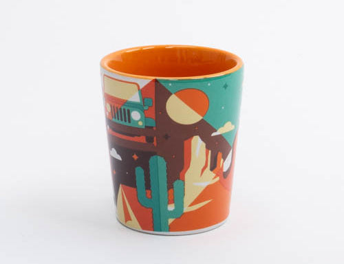 Ceramic Moab shot glass with a red rock landscape and cactus silhouettes