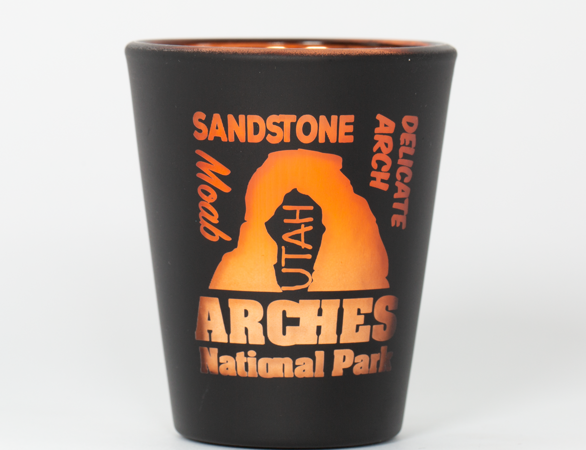 Matte black Moab shot glass with an etched design and orange electroplated interior