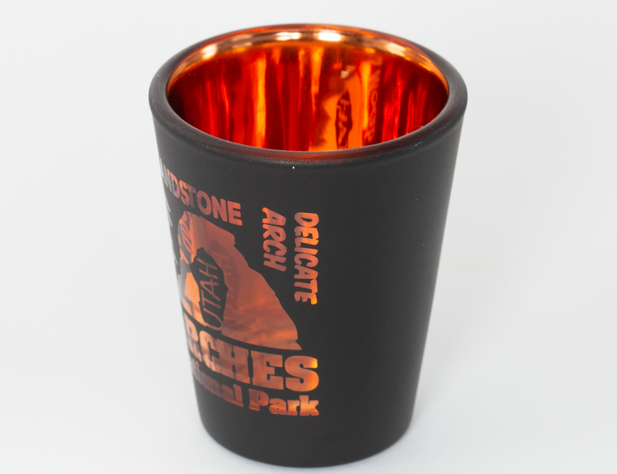 Matte black Moab shot glass with an etched design and orange electroplated interior, second view