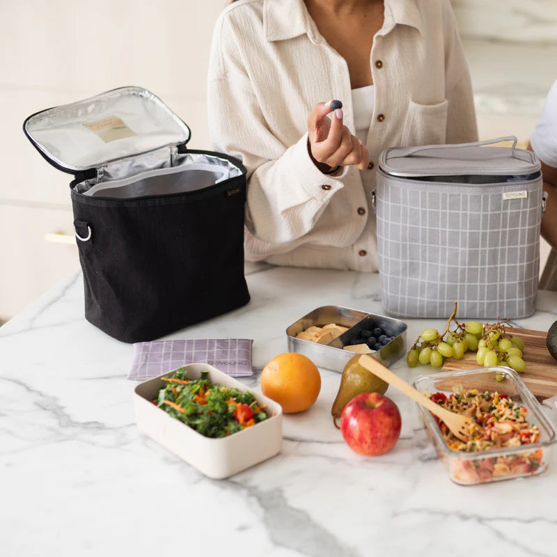 SoYoung Lunch Poche in black open on a marble table with packed lunch containers and fruit