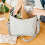 Hands packing food containers into the SoYoung Lunch Poche in gray at a kitchen table