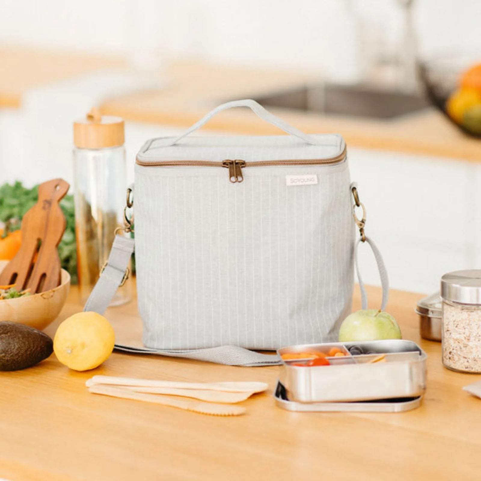SoYoung Lunch Poche in Pinstripe Heather Grey on a kitchen counter with fruit and a water bottle