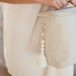 SoYoung Single Beaded Tassel in Cream hanging from a linen lunch bag