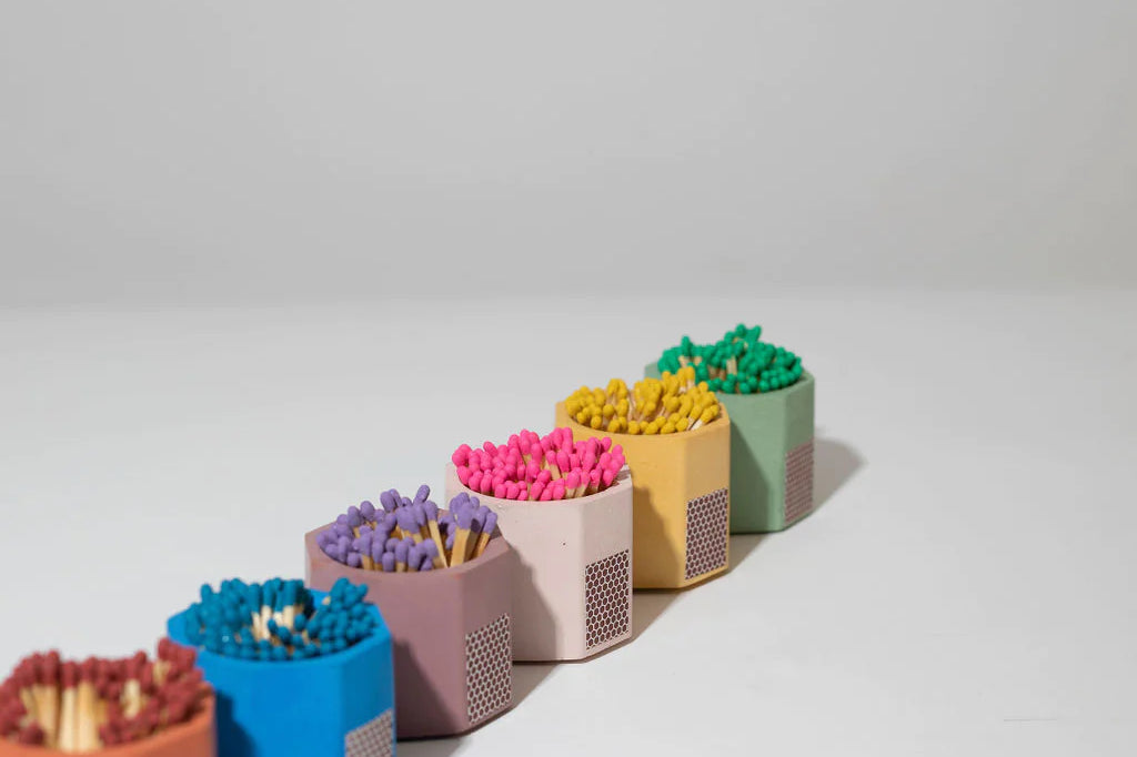Row of Tenn Prairie Concrete Match Holders in assorted colors filled with colorful matches
