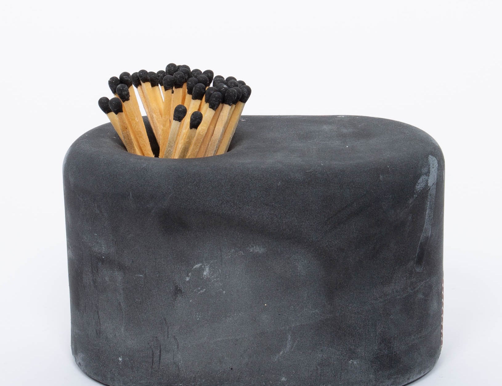 Tenn Prairie Streamliner Match Holder in Charcoal, a rounded black concrete holder with black-tipped matches