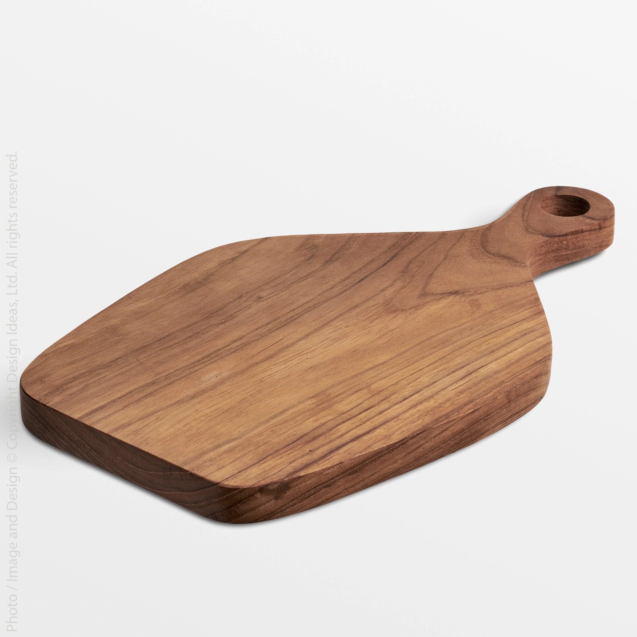 Texxture Chiku Teak Cutting Board, a warm brown paddle-shaped board with a handle hole