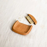 The Collective Belfort Crumb Brush Set, a natural wood dustpan and bristle brush on white linen