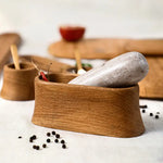 The Collective Belfort Oak Mortar and Marble Pestle close up with peppercorns and wooden serving boards behind