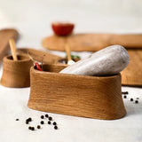 The Collective Belfort Oak Mortar and Marble Pestle close up with peppercorns and wooden serving boards behind