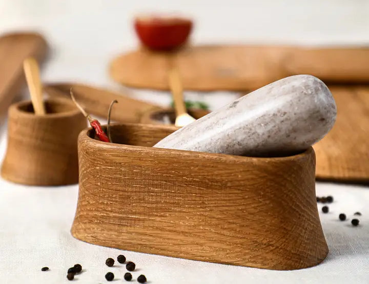 The Collective Belfort Oak Mortar and Marble Pestle close up with peppercorns and wooden serving boards behind