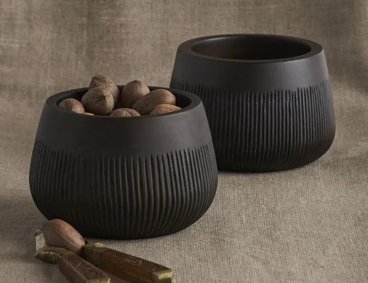 The Collective Chiseled Leila Bowls, two matte black ribbed bowls, one filled with nuts, on linen