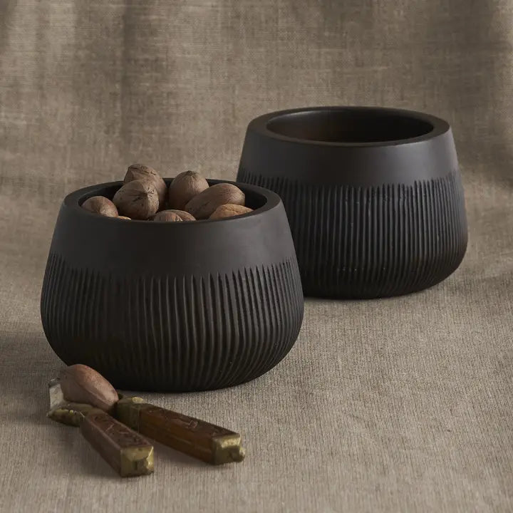 The Collective Chiseled Leila Bowls, two matte black ribbed bowls, one filled with nuts, on linen