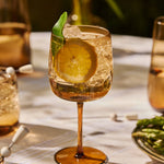 The Collective Ember Wine Glass with a spritz, lemon and herb garnish on an outdoor table