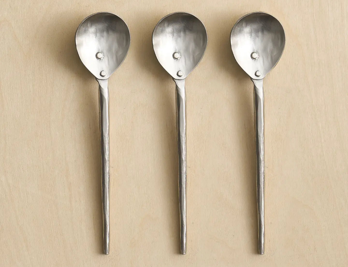 The Collective Forge Pewter Small Spoons Set of 3, hammered silver spoons in a row