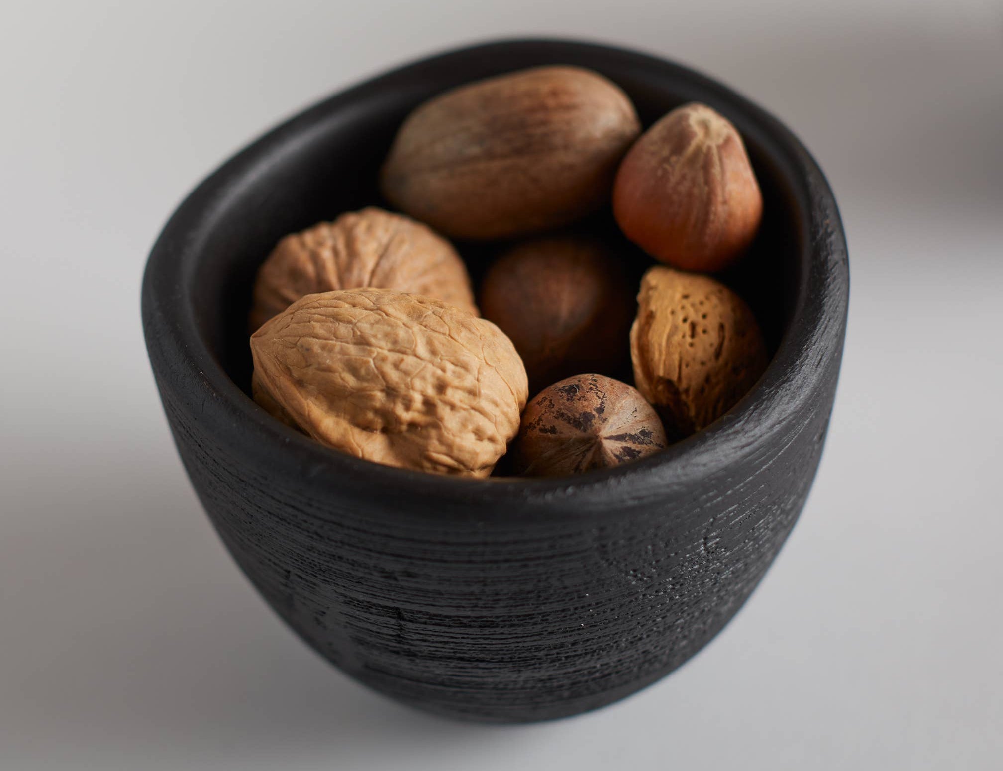 The Collective Groove Tidbit Bowl in black filled with whole walnuts, close-up
