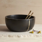 The Collective Mondrian Serving Bowl, a black wooden bowl with a brass inlay stripe and gold servers