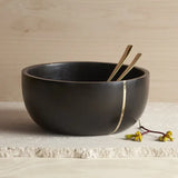 The Collective Mondrian Serving Bowl, a black wooden bowl with a brass inlay stripe and gold servers