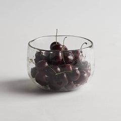 The Collective Pebbled Bowls Set of 2, a textured glass bowl filled with cherries