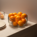 The Collective Pebbled Salad Bowl filled with oranges on a table with stacked plates