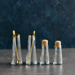 The Collective Pebbled Small Carafes and shakers with cork stoppers and gold spoons on a dark surface