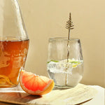 The Collective Pebbled Small Glasses with a carafe of tea and grapefruit slices on a wooden board