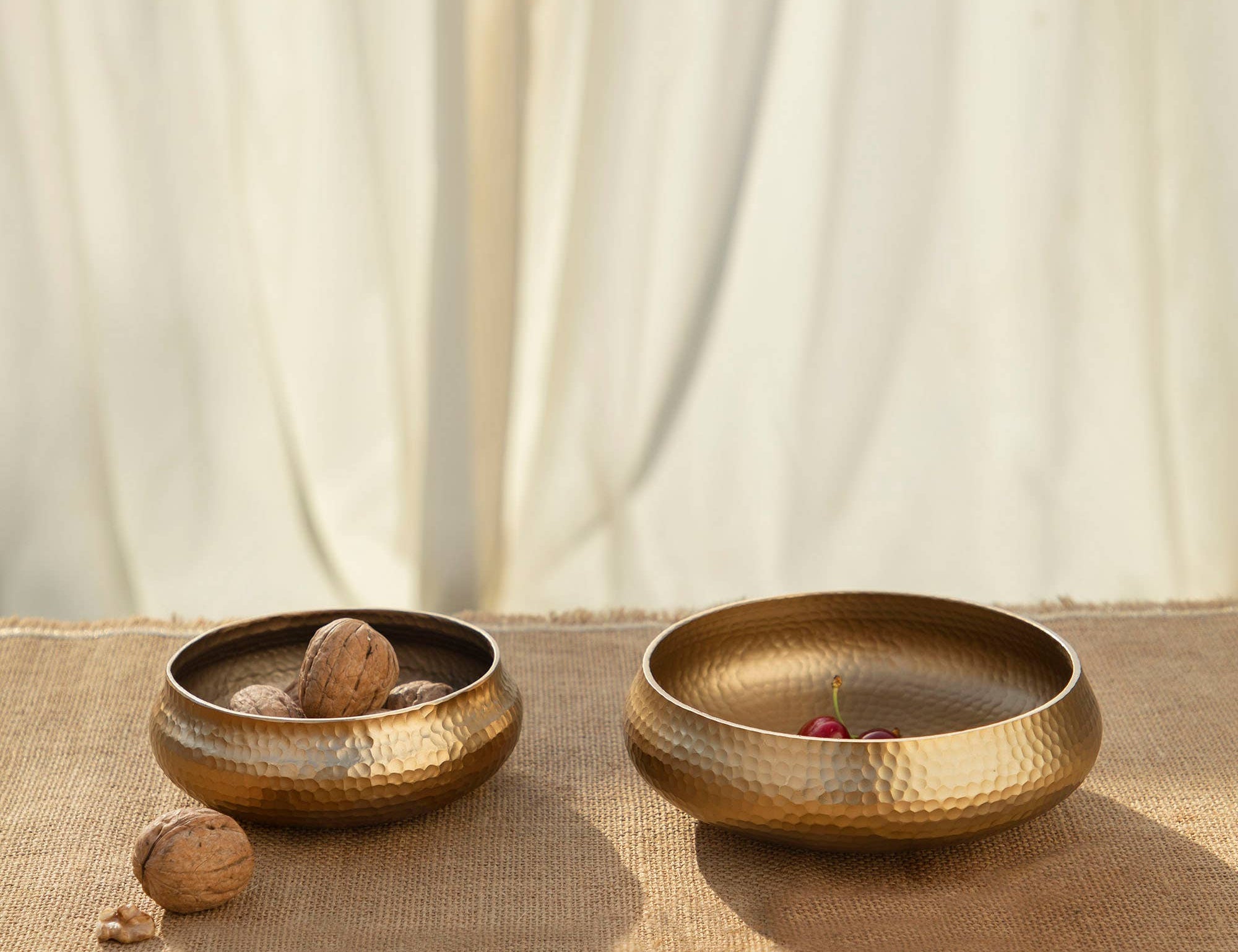 The Collective Pebbled Snack Bowls Set of 2, two hammered brass bowls with walnuts on burlap