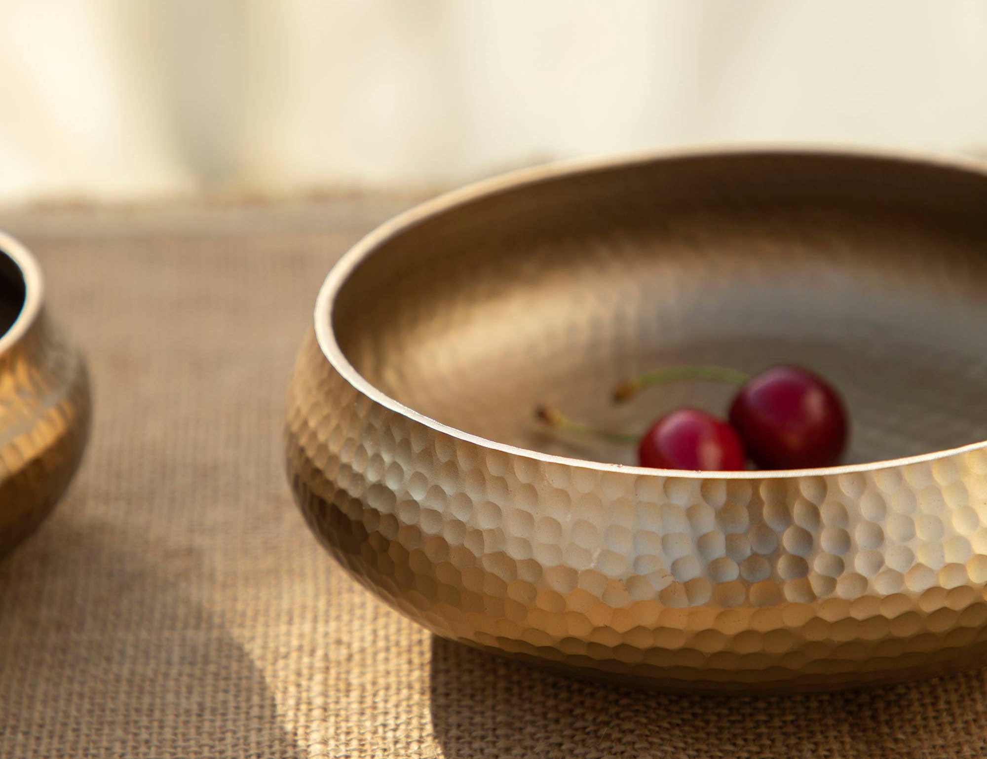 Close-up of The Collective Pebbled Snack Bowls in hammered brass with cherries