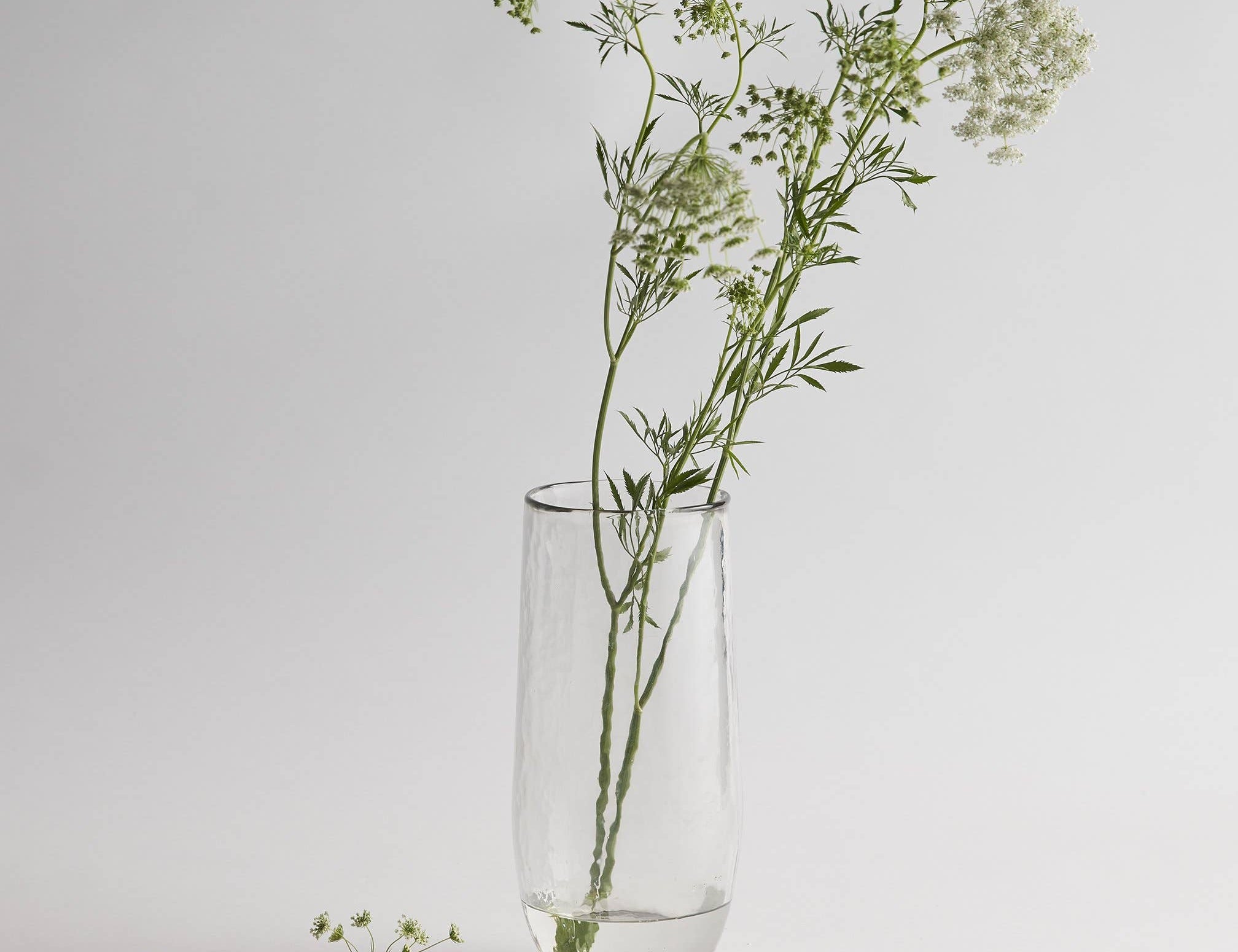 The Collective Pebbled Tall Vase, a slim textured glass vase holding wildflower stems
