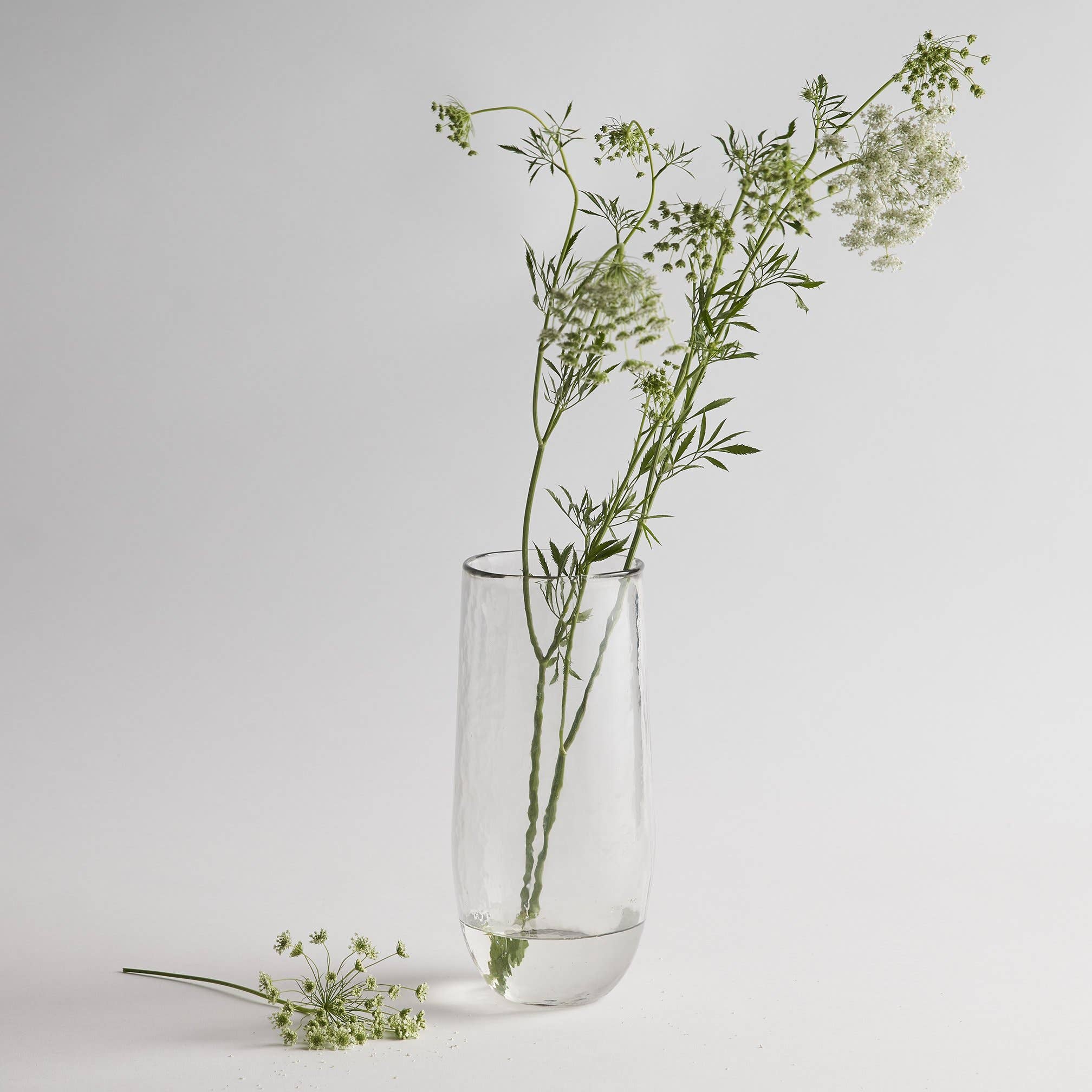 The Collective Pebbled Tall Vase, a slim textured glass vase holding wildflower stems